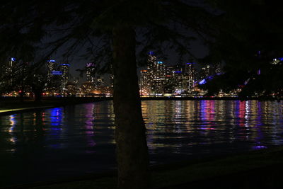 Illuminated city by river at night