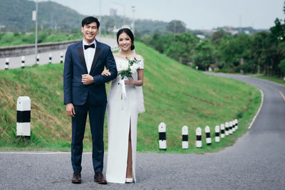 Portrait of smiling young couple standing on road