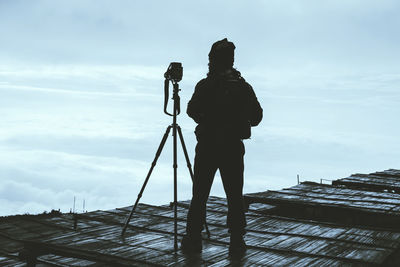 Rear view of silhouette man photographing against sky