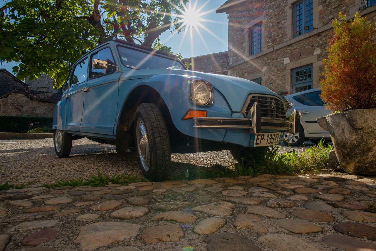 car, mode of transportation, transportation, motor vehicle, vehicle, architecture, building exterior, built structure, land vehicle, nature, tree, city, vintage car, plant, street, building, antique car, retro styled, no people, sunlight, day, sky, outdoors, wheel, subcompact car, travel, off-roading, blue, automobile