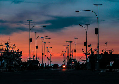 Cars on street against sky at sunset