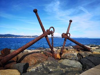 Rusty chain on rock by sea against sky