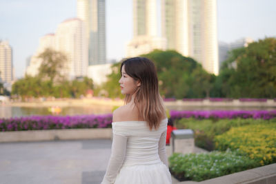 Young woman standing against buildings