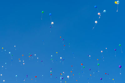 Low angle view of balloons flying against blue sky