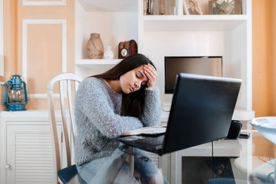 Young woman using phone while sitting at home