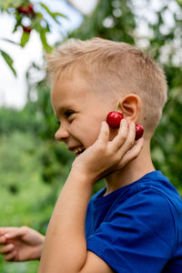 Candid portrait of a boy in the orchard during cherries harvesting.