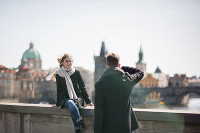 Rear view of man and woman against sky in city