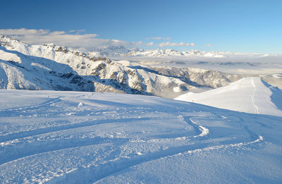 Scenic view of snow covered mountains against blue sky