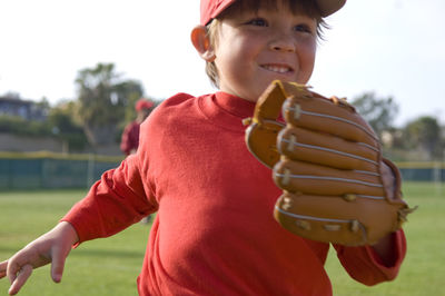 Close up of young boy running off the tball fiels with a big smile