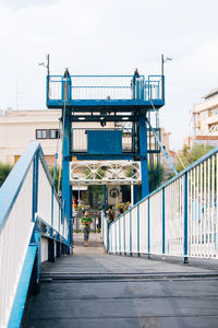 Woman walking on walkway in city against clear sky
