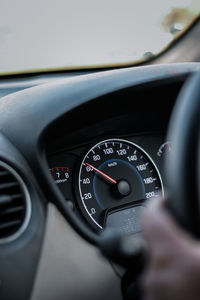 Cropped hand holding steering wheel while sitting at car