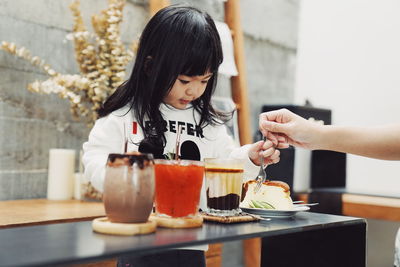 Cropped hand feeding girl