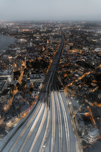 Aerial view of light trails on street amidst cityscape at sunset