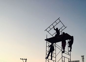 Low angle view of silhouette man working against clear sky