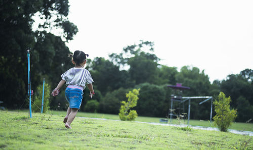 Rear view of boy running on field