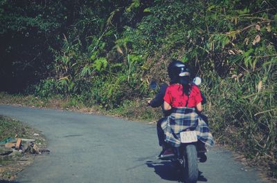 Rear view of woman riding bicycle on road