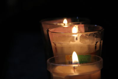 Close-up of burning candle against black background