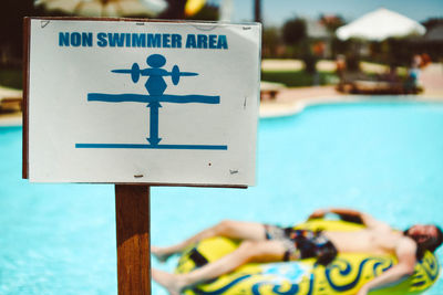 Close-up of sign by swimming pool