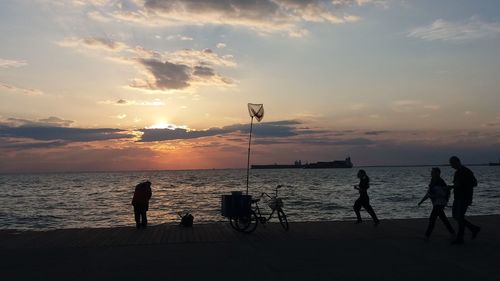 People on sea against sky during sunset