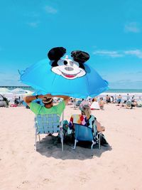 People at beach against blue sky