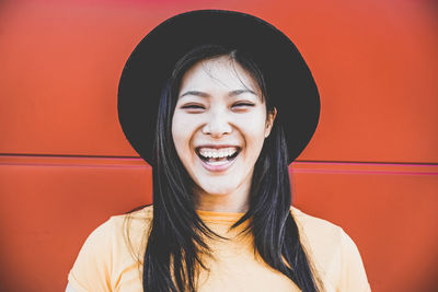 Portrait of smiling young woman against red wall