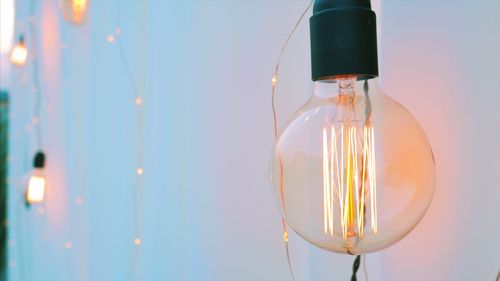 Close-up of illuminated light bulb against sky