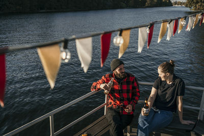 Friends holding beer bottles sitting on boat deck