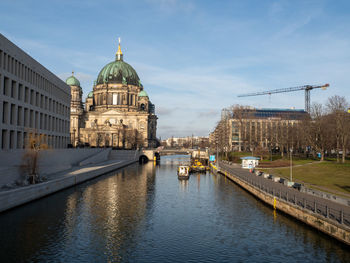 Buildings by river against sky