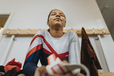 Female athlete with eyes closed sitting in locker room