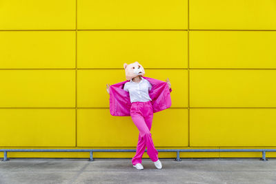 Full length of girl standing against yellow wall