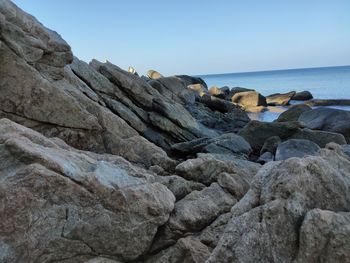 Rock formations on shore against clear sky
