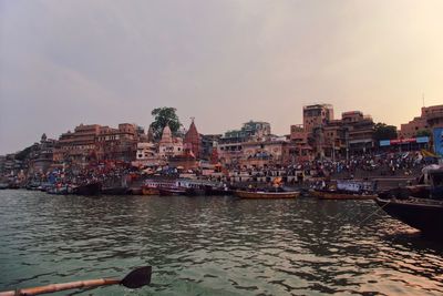 Scenic view of river by buildings against sky at sunset