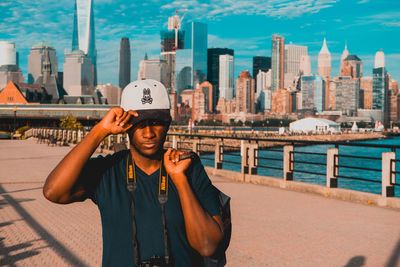 Portrait of young man standing against buildings in city