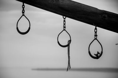 Close-up of chain hanging on wood against sky