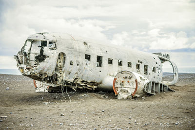 Abandoned airplane at beach against sky