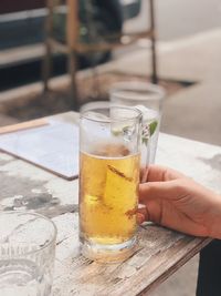 Close-up of hand holding drink on table