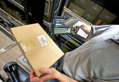 Midsection of man scanning barcode on box