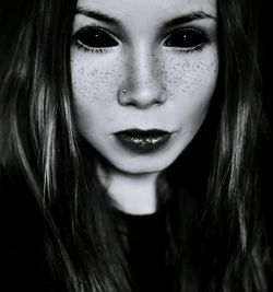 Close-up portrait of beautiful young woman against black background