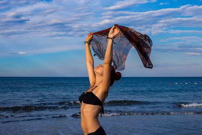Midsection of woman standing at beach against sky
