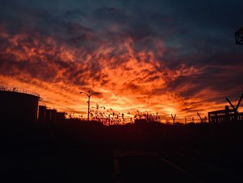 Silhouette buildings against dramatic sky during sunset