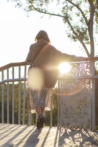 Rear view full length of woman standing by railing