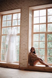 Woman sitting on window sill at home