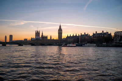 View of river and buildings against sky during sunset