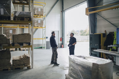 Male workers discussing while standing by entrance of lumber industry