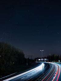 Light trails on road against sky at night