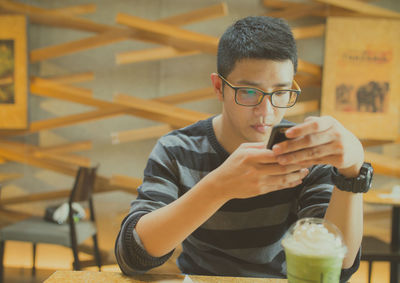 Man using mobile phone while sitting in cafe