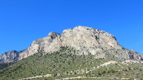 Low angle view of rock formation against clear blue sky