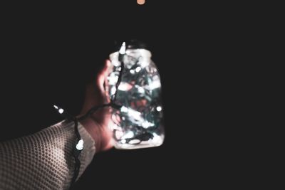 Close-up of hand holding glass against black background