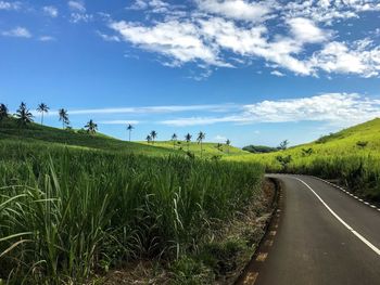 Panoramic view of road amidst field against sky