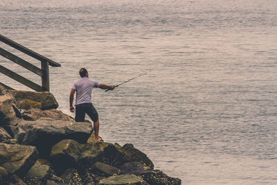 Rear view of man fishing in sea